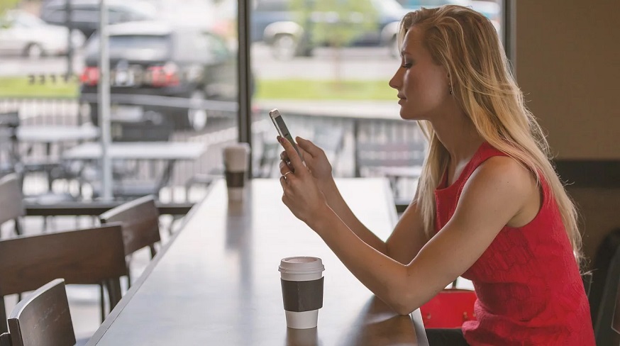 Reader Optimize - Woman looking at phone whie sitting at a counter