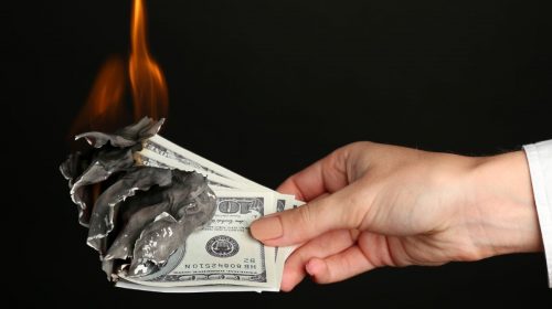 Wildfire insurance - person holding money that's on fire