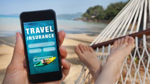 Travel insurance - person on hammok on beach looking at phone
