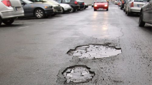 Auto insurance - car driving toward potholes