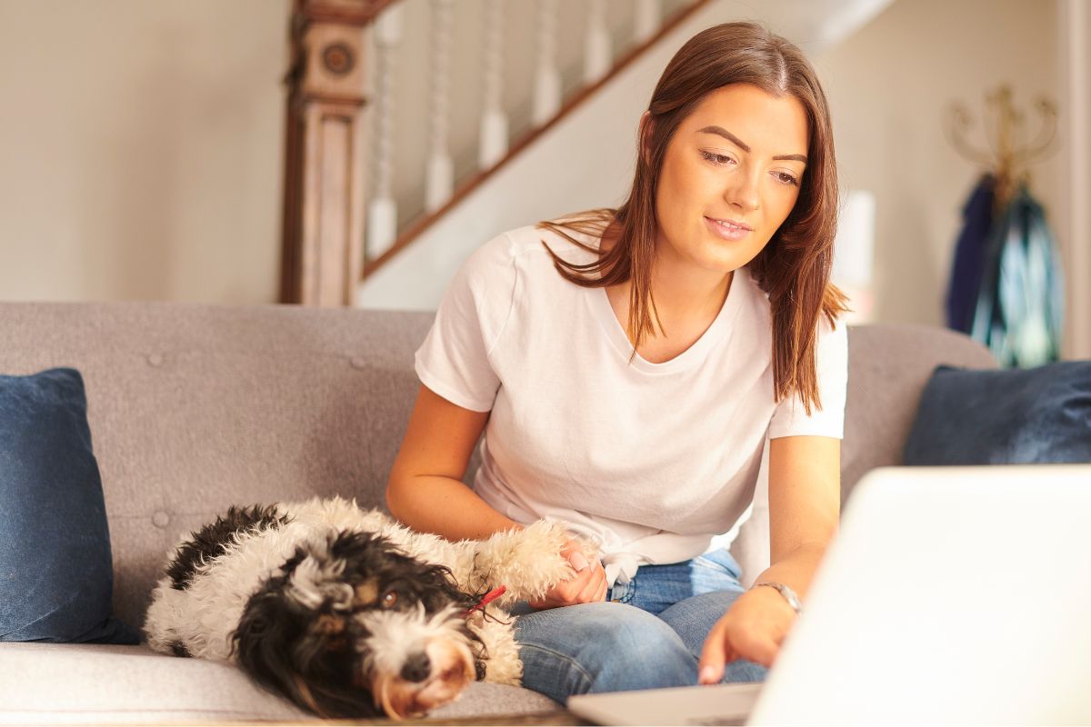 Pet Insurance - Person on computer beside her dog