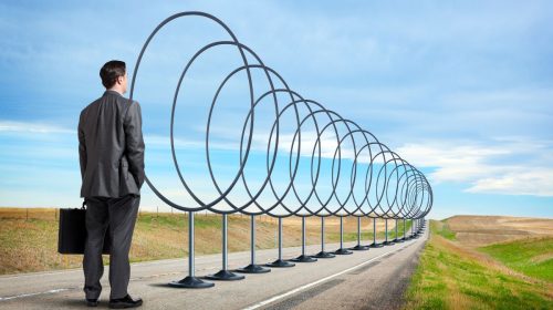 Auto insurance - Business person standing on road looking at hoops to jump through