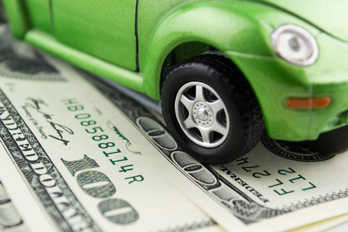 Auto insurance Costs - green car on top of US money