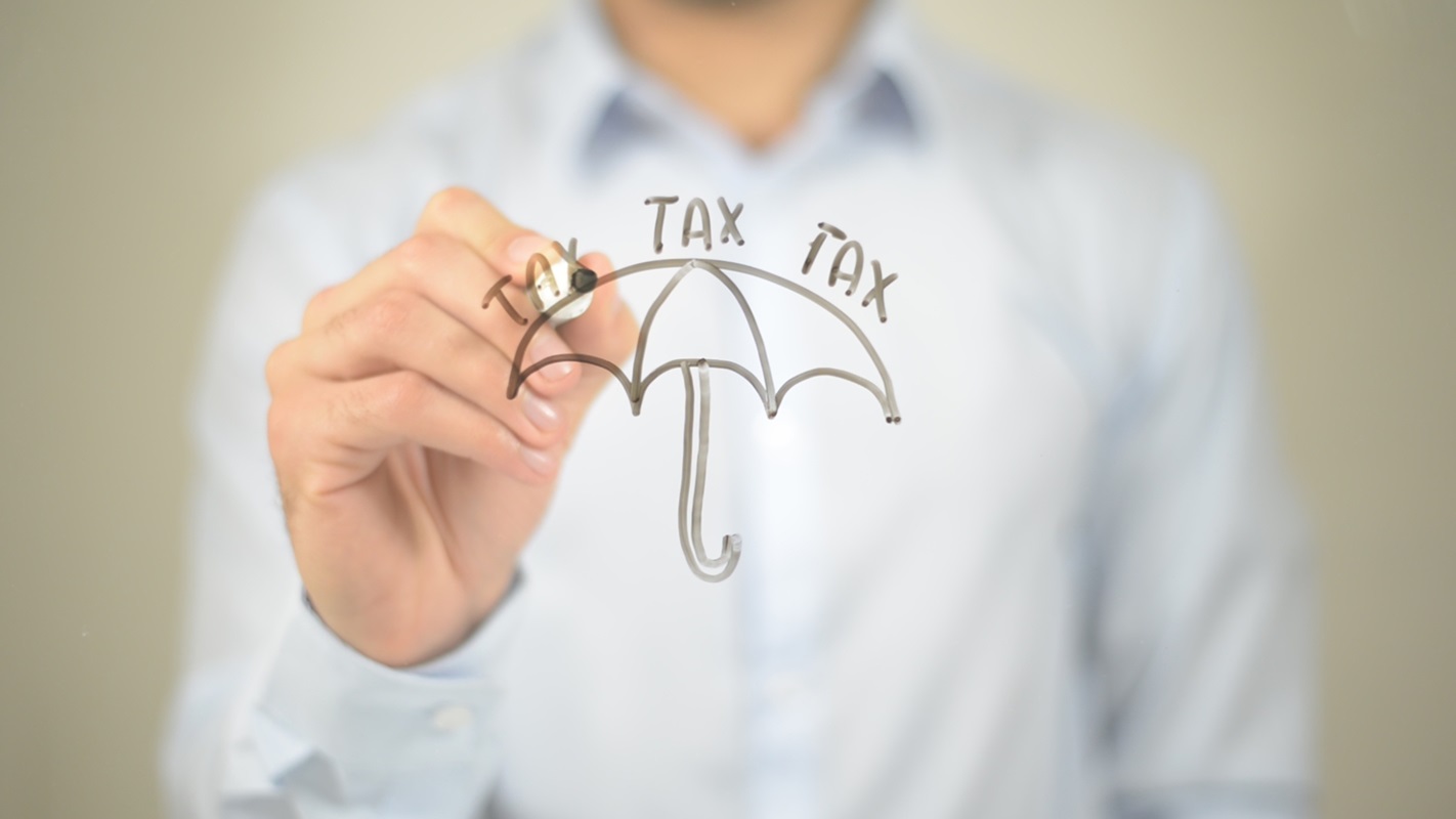 Business insurance - Person writing the word tax on top of an umbrella